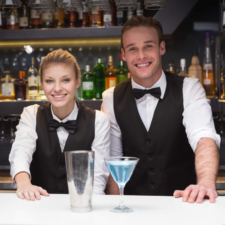 Deux employés d'un bar servent un cocktail